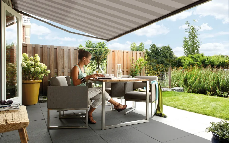 terras met wit en beige gestreept knikarmscherm als buitenzonwering