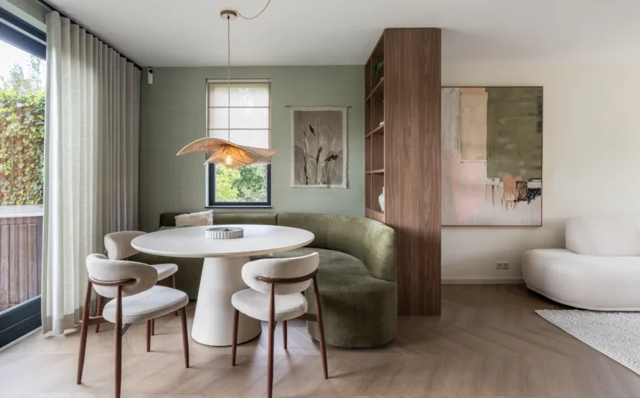 Eetkamer met witte stoelen en groene bank met donker bruine kast op maat