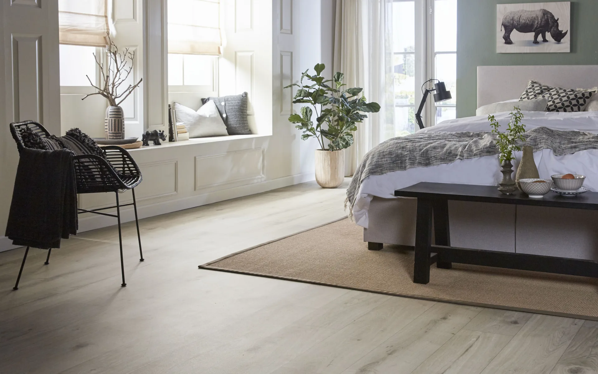 Slaapkamer met houtlook vinylvloer, vouwgordijnen in pasteltinten en groot tweepersoonsbed.