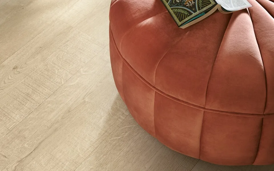 Lichte houtlook vinylvloer van Pergo met een roze poef