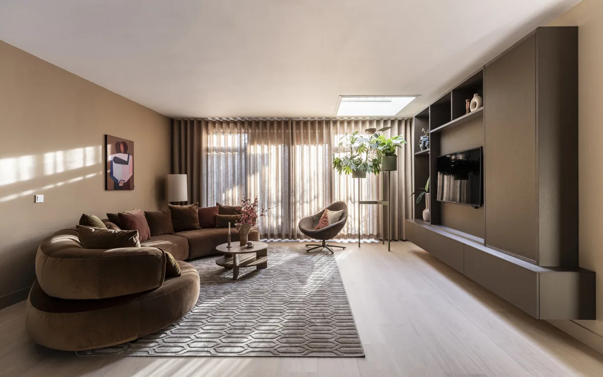 Woonkamer met houten vloer, transparante Luxaflex gordijnen en beige Allure kast op maat