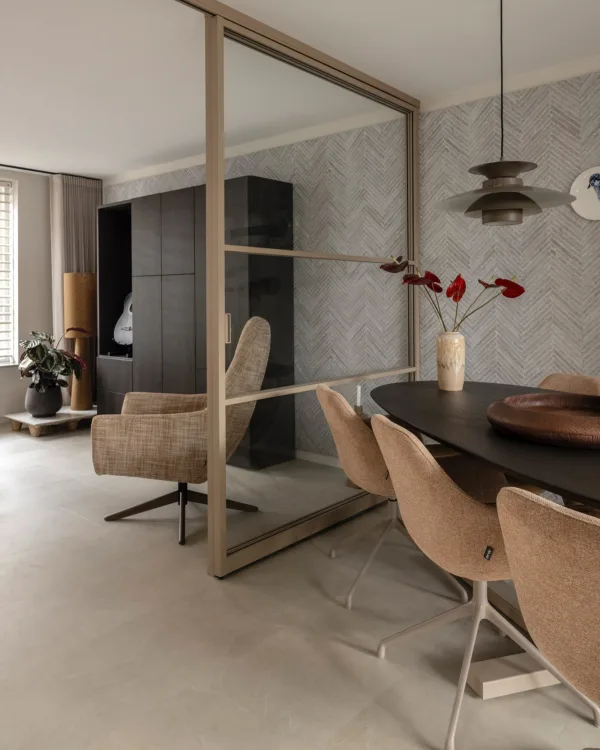 Woonkamer met betonlook tegels, metalen deuren en ovale eettafel