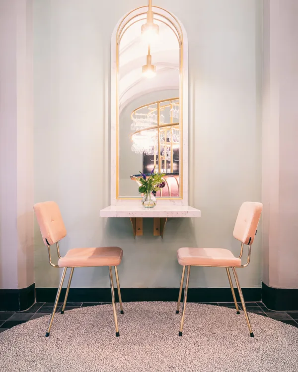 Detail rond wollen vloerkleed met stoeltjes en spiegel.