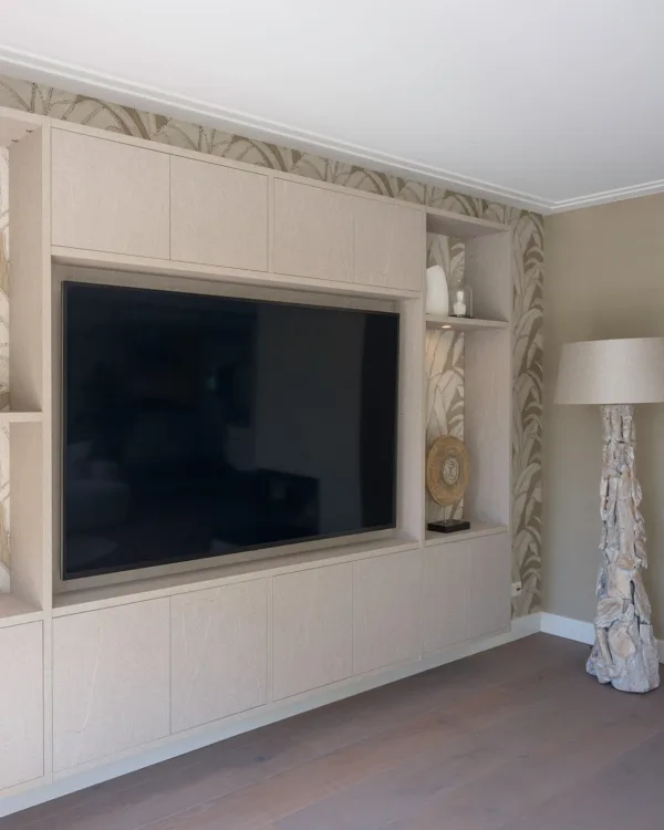 Cinewall in lichte houtkleur, met grote tv, draaideuren zonder greep en open vakken met planken voor accessoires.
