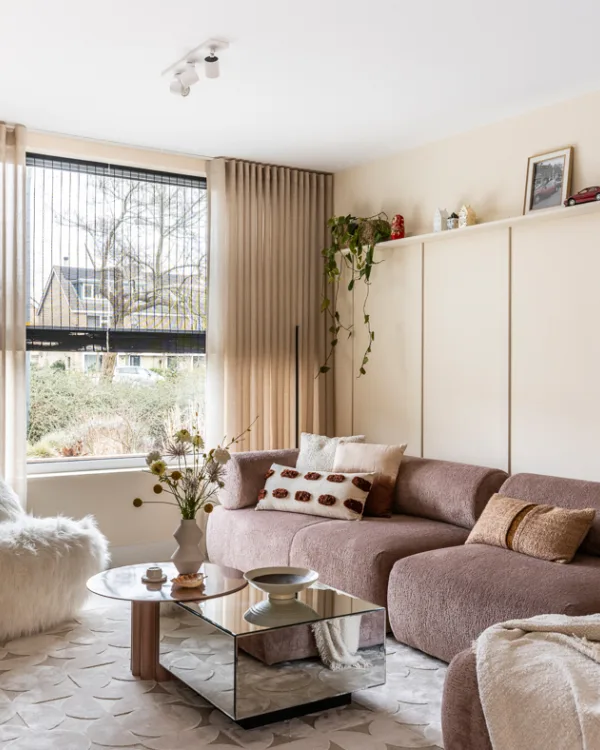 Gezellige zithoek met dubbele raamdecoratie: vitrage en geweven hout rolgordijnen.