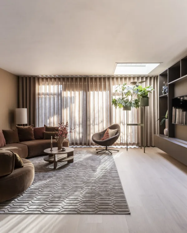 Woonkamer met houten vloer, transparante Luxaflex gordijnen en beige Allure kast op maat