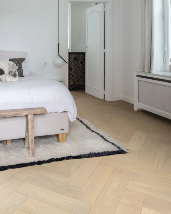 Lichte parketvloer in visgraatmotief in de slaapkamer