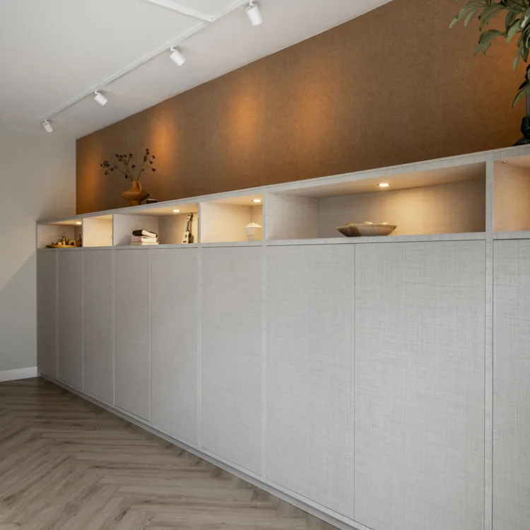 Woonkamer met wandkast op maat inclusief verlichting, structuurbehang en visgraatvloer. | Aanhuis.be