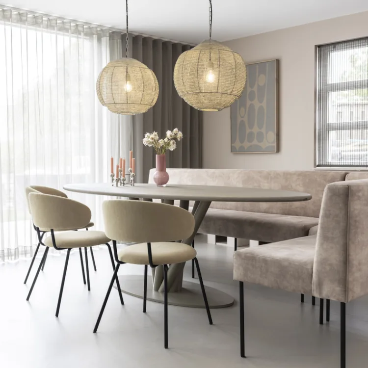Eetkamer in natuurlijke stijl met ovale tafel en vitrages en overgordijnen voor grote raampartij.