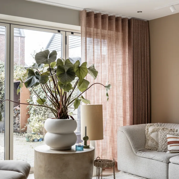 Woonkamer met roestbruine gordijnen, warme materialen en sfeervolle accessoires