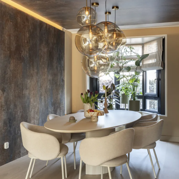 Eetkamer met ovale tafel, witte stoelen en steenlook muur