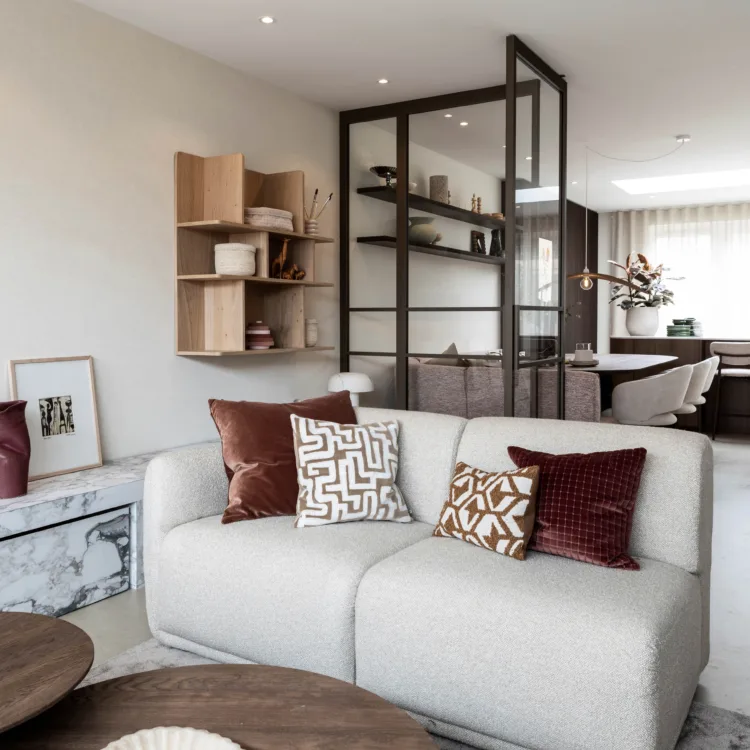 Living met een grijze bank en een stalen afscheiding met glas