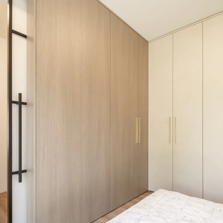 Slaapkamer met ingebouwde draaideurkasten op maat in twee verschillende kleuren voor een ruimtelijk effect.